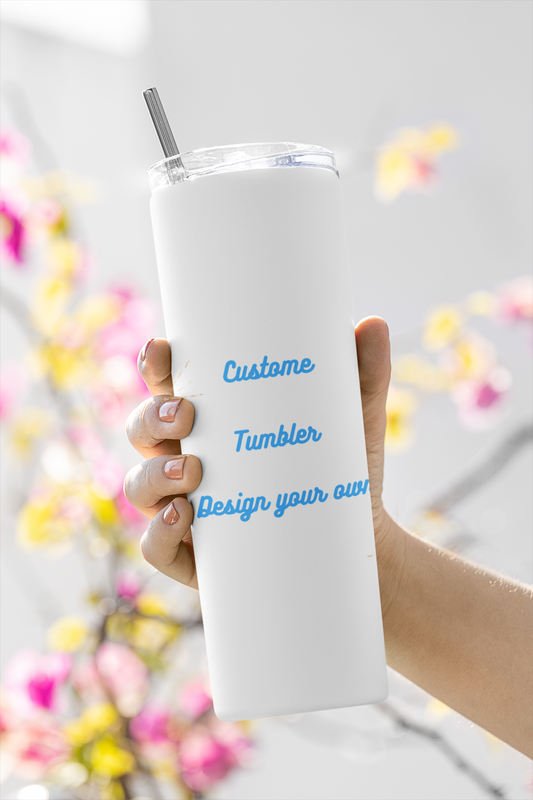 Hand holding white personalized skinny tumbler with straw and blue custom text against floral background